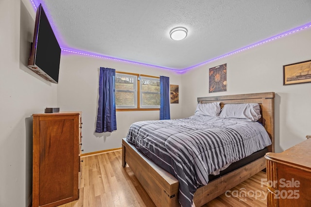 bedroom featuring light wood-type flooring, a textured ceiling, and baseboards