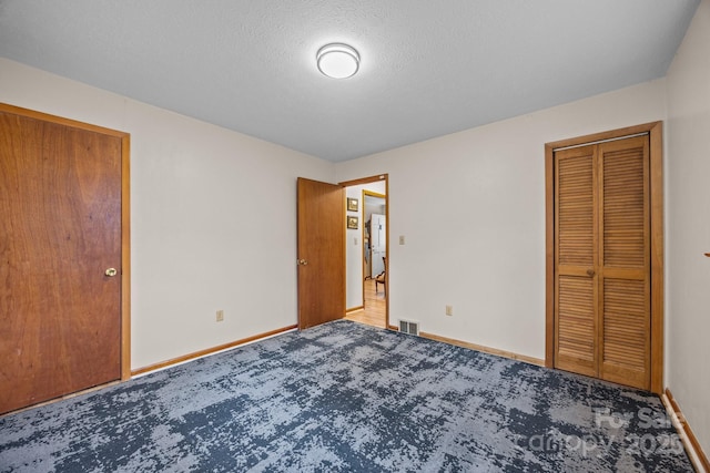 unfurnished bedroom featuring a textured ceiling, carpet, visible vents, and baseboards