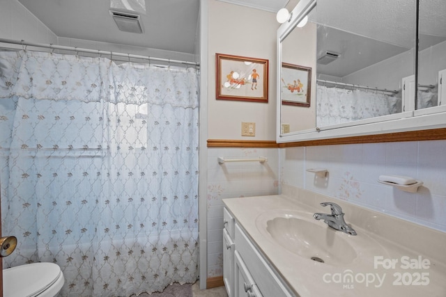 bathroom with curtained shower, toilet, visible vents, vanity, and tile walls