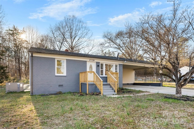 view of front of house with brick siding, a front yard, crawl space, an attached carport, and driveway