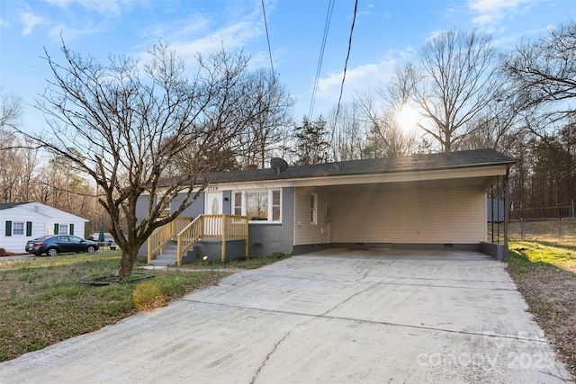 view of front facade featuring brick siding, concrete driveway, crawl space, fence, and an attached carport