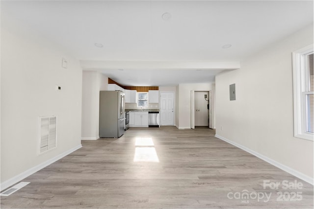 unfurnished living room with visible vents, light wood finished floors, and baseboards