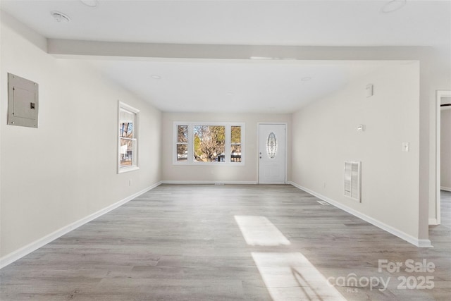 unfurnished living room with baseboards, electric panel, visible vents, and wood finished floors