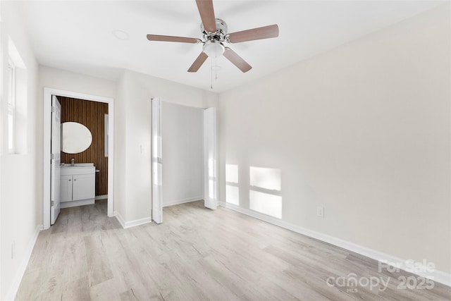 unfurnished bedroom featuring baseboards, a ceiling fan, connected bathroom, light wood-style floors, and a sink