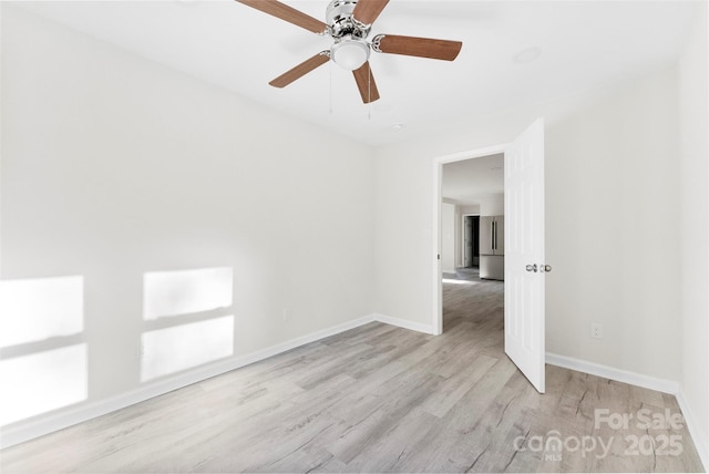 empty room featuring a ceiling fan, baseboards, and wood finished floors