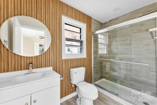 full bath featuring vanity, wood finished floors, a shower stall, and toilet