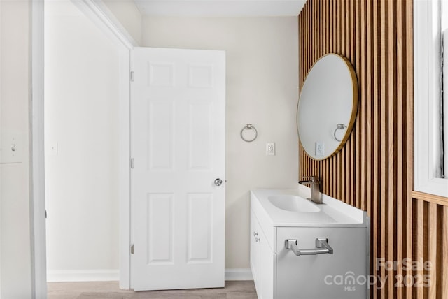 bathroom with baseboards, wood finished floors, and vanity