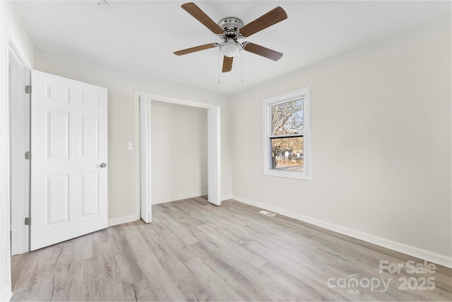 unfurnished bedroom featuring ceiling fan, wood finished floors, visible vents, baseboards, and a closet