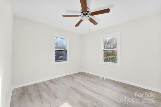 empty room featuring ceiling fan, wood finished floors, visible vents, and baseboards