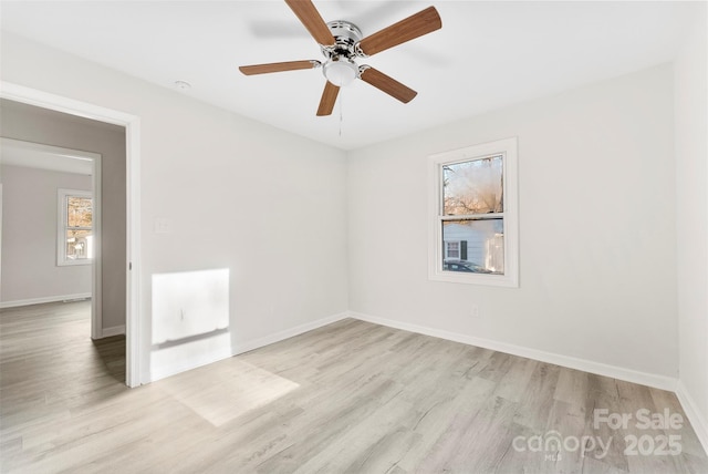 spare room featuring a ceiling fan, light wood-type flooring, and baseboards