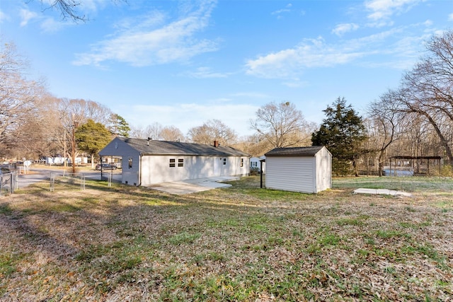 view of yard featuring a patio, an outdoor structure, fence, a gate, and a storage unit