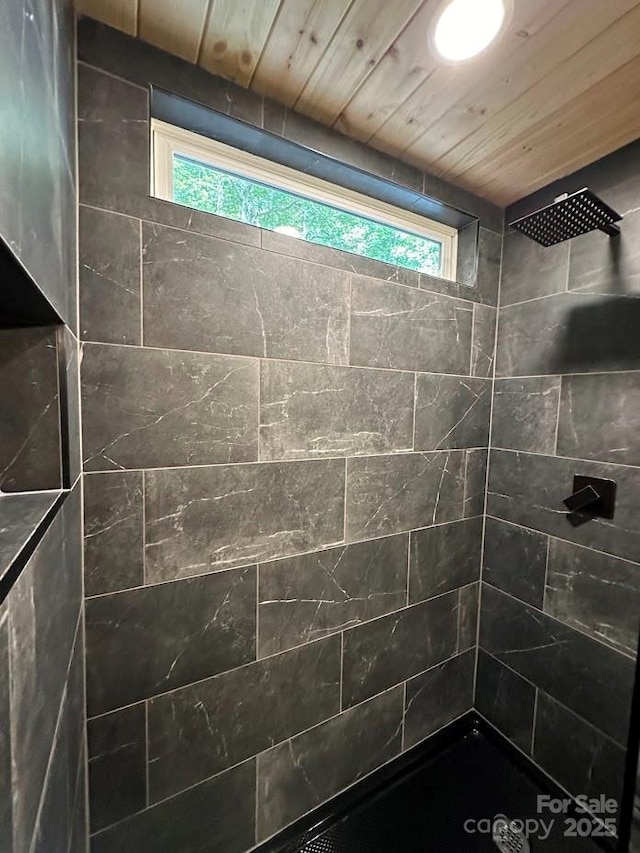 bathroom featuring a tile shower, wood ceiling, and a healthy amount of sunlight