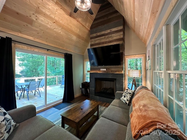 living area featuring a ceiling fan, a glass covered fireplace, wood ceiling, and wood finished floors