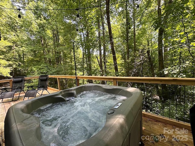 wooden terrace featuring a view of trees and a hot tub