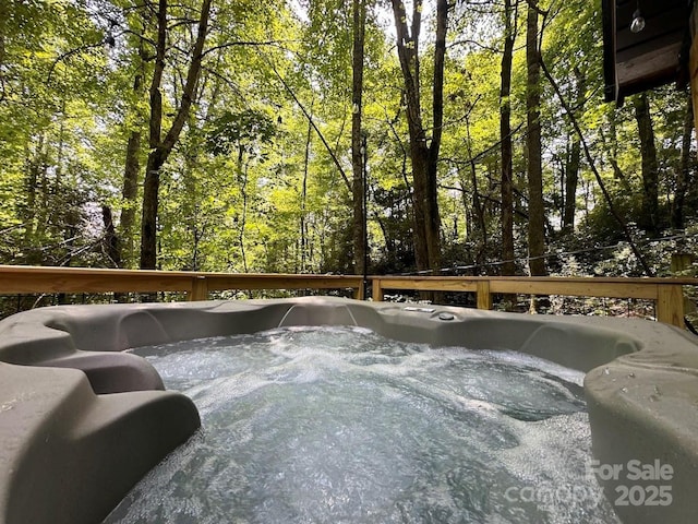 wooden deck with a forest view and a hot tub