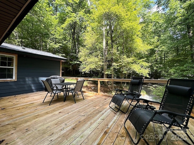 wooden deck with outdoor dining area and a forest view