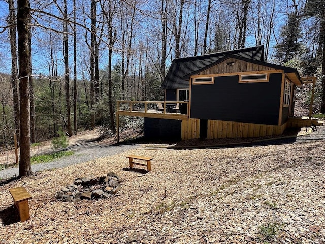 view of side of property with a fire pit, board and batten siding, and a wooden deck