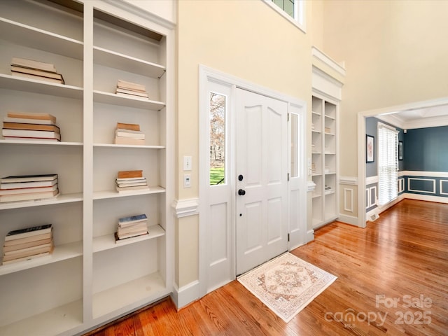 foyer with a healthy amount of sunlight, crown molding, a high ceiling, and wood finished floors