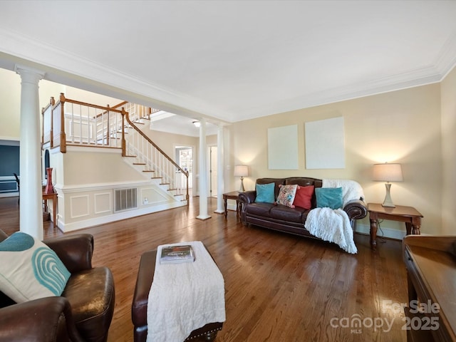 living area with decorative columns, visible vents, stairway, ornamental molding, and wood finished floors