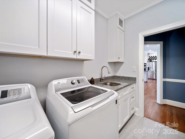 laundry room featuring washing machine and dryer, a sink, baseboards, cabinet space, and crown molding