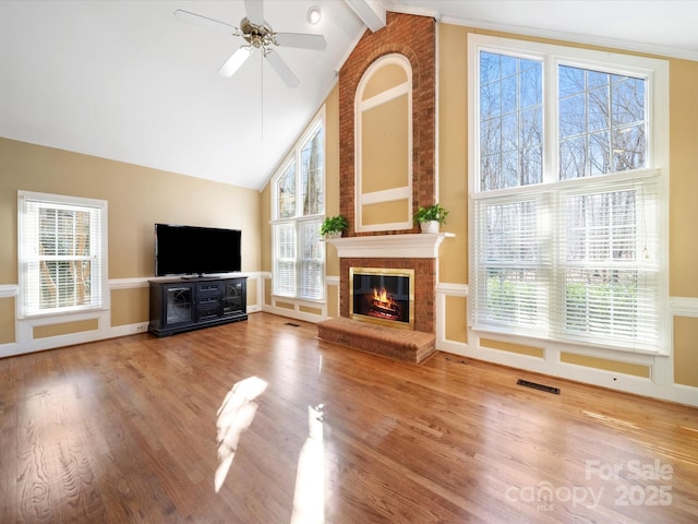 unfurnished living room with a healthy amount of sunlight, visible vents, a fireplace, and wood finished floors