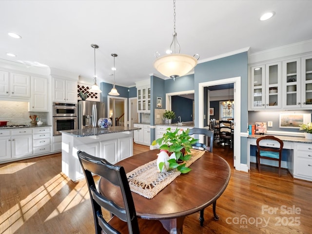 dining area featuring built in desk, ornamental molding, wood finished floors, and recessed lighting