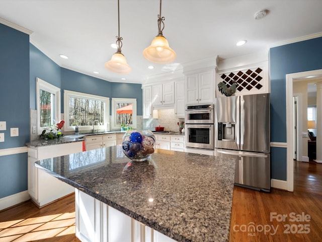 kitchen with appliances with stainless steel finishes, white cabinetry, ornamental molding, and backsplash