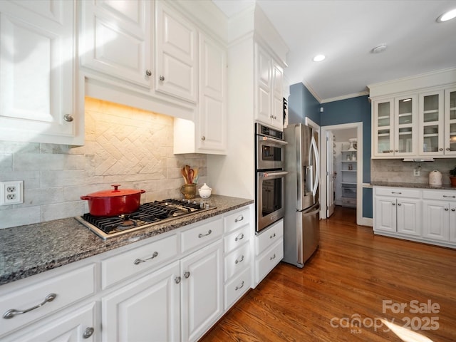 kitchen featuring white cabinets, glass insert cabinets, appliances with stainless steel finishes, wood finished floors, and crown molding