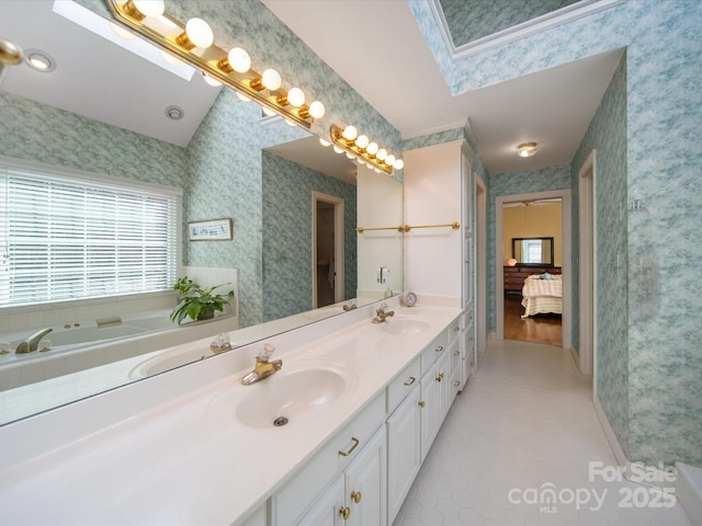 bathroom featuring a sink, connected bathroom, and wallpapered walls