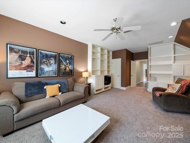 carpeted living area with baseboards, visible vents, a ceiling fan, vaulted ceiling, and built in shelves