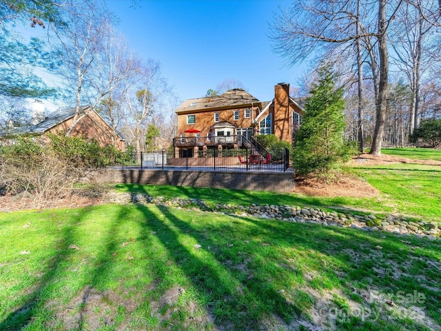 back of house with a deck, a lawn, a chimney, and fence