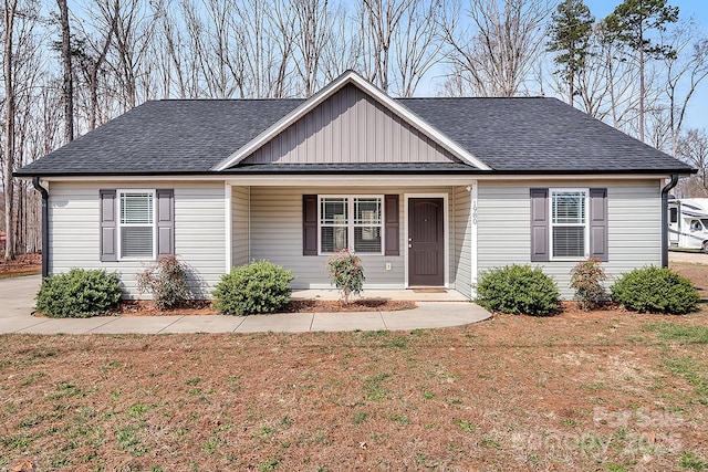 single story home with roof with shingles, a front yard, and board and batten siding