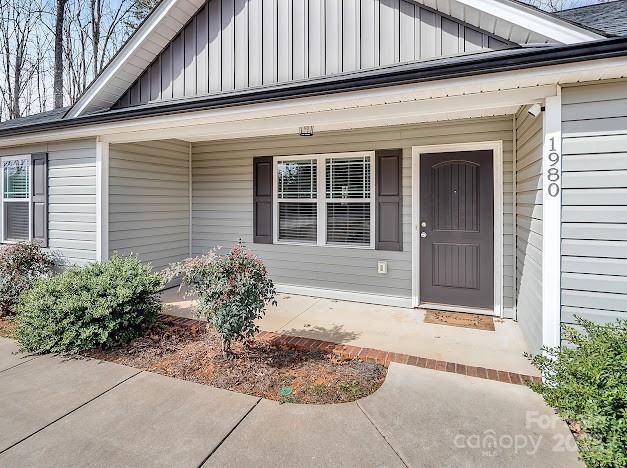 doorway to property with board and batten siding and a porch