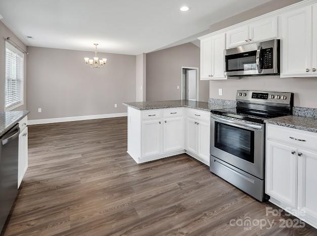 kitchen featuring dark wood-style floors, a peninsula, appliances with stainless steel finishes, and white cabinetry