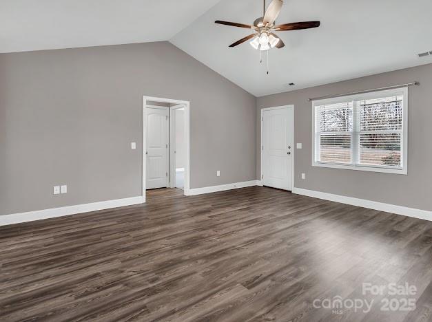 spare room with vaulted ceiling, dark wood finished floors, a ceiling fan, and baseboards