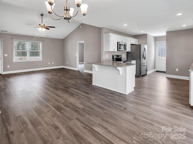 kitchen featuring baseboards, appliances with stainless steel finishes, open floor plan, white cabinetry, and ceiling fan with notable chandelier