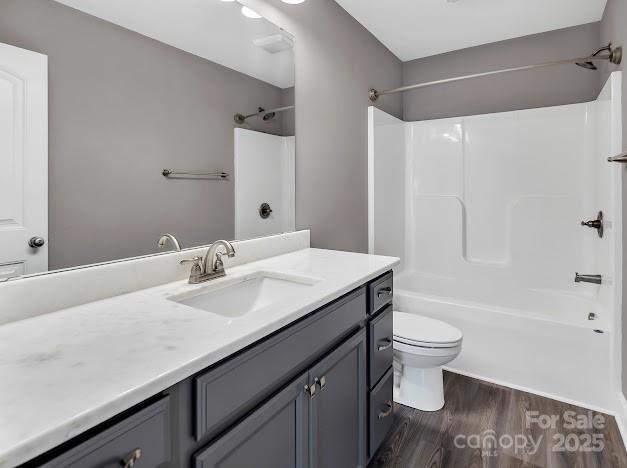 bathroom with toilet,  shower combination, wood finished floors, and vanity