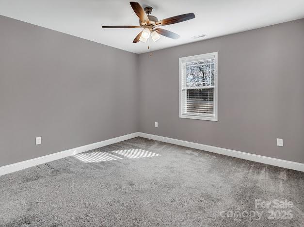 carpeted empty room with baseboards and a ceiling fan