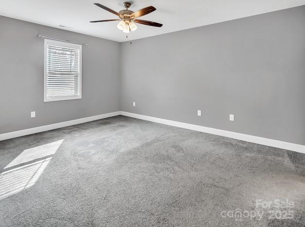 carpeted spare room with ceiling fan and baseboards