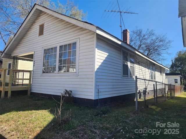 view of property exterior with a lawn, a chimney, and fence