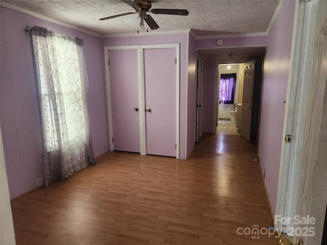 hall featuring crown molding, wooden walls, and light wood-style floors