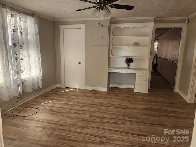 unfurnished bedroom with ornamental molding, a ceiling fan, baseboards, and wood finished floors