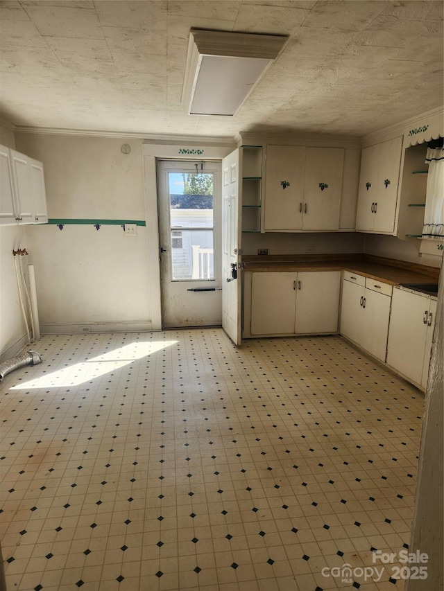 kitchen featuring dark countertops, crown molding, cream cabinets, and open shelves