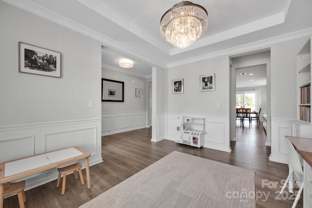 interior space with an inviting chandelier, dark wood-style flooring, a decorative wall, and a raised ceiling