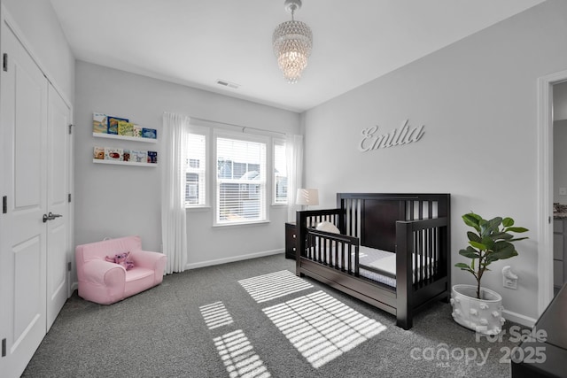 bedroom with a crib, carpet, baseboards, a notable chandelier, and visible vents