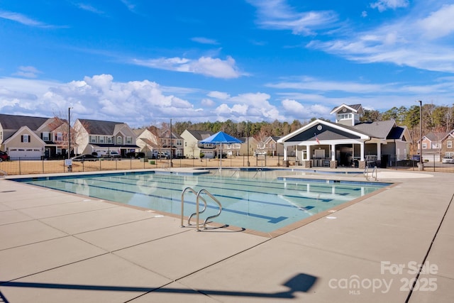 pool with a patio area, fence, and a residential view