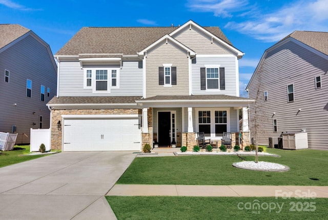 craftsman-style house with a front lawn, driveway, a porch, and stone siding