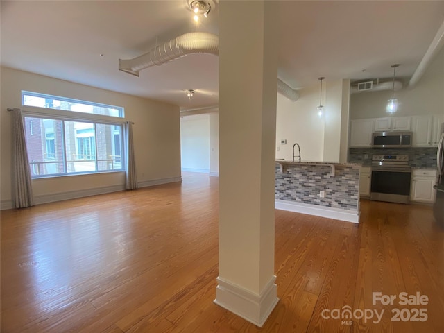 interior space featuring visible vents, white cabinets, open floor plan, appliances with stainless steel finishes, and decorative backsplash