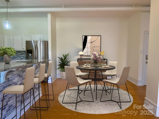 dining space with baseboards and light wood-style floors