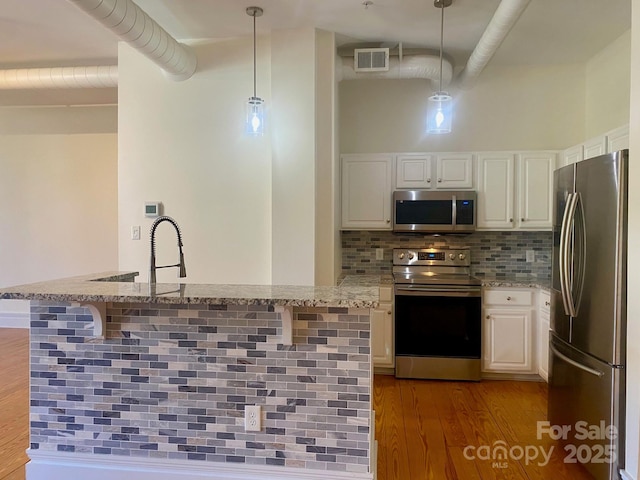 kitchen featuring appliances with stainless steel finishes, visible vents, backsplash, and light stone counters